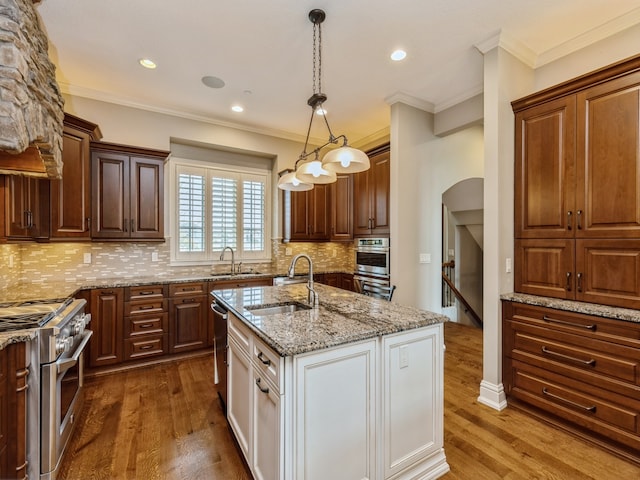 kitchen with dark wood-style flooring, arched walkways, stainless steel appliances, and a sink