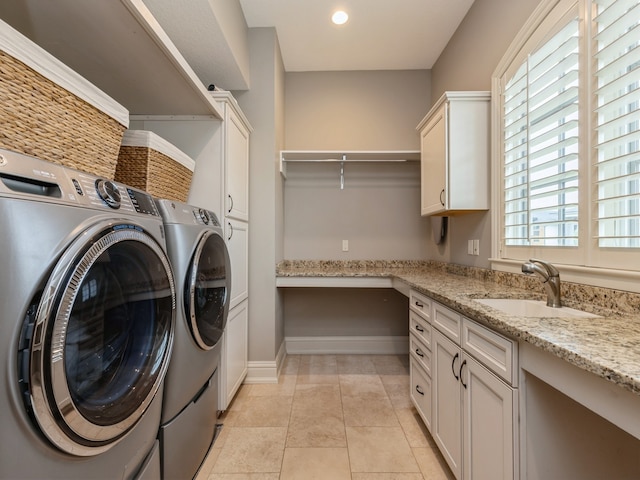 clothes washing area featuring cabinet space, light tile patterned floors, baseboards, washer and clothes dryer, and a sink