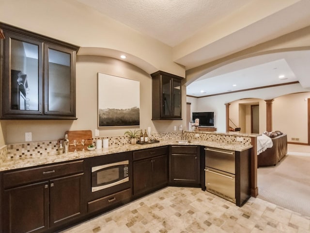 3123 162nd St, Urbandale, IA 50323 - kitchen with built in microwave, arched walkways, decorative columns, a peninsula, and light stone countertops
