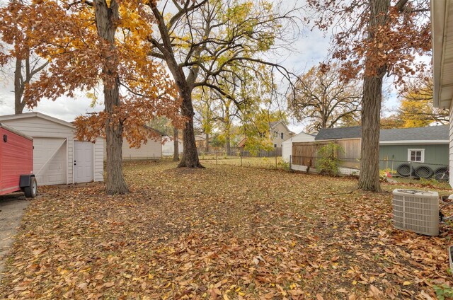 view of yard with a garage, fence, central AC, and an outdoor structure