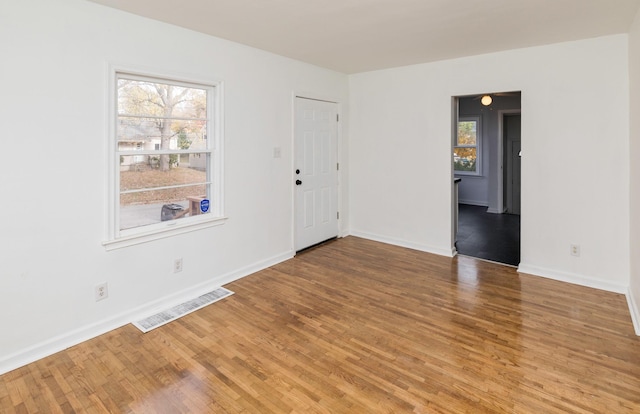 empty room with wood finished floors, baseboards, and visible vents