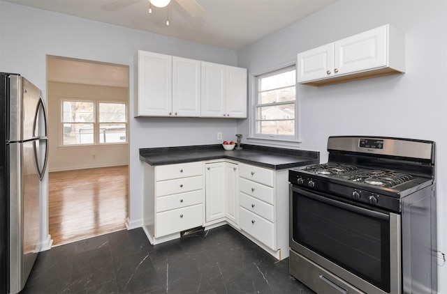 kitchen featuring ceiling fan, stainless steel appliances, dark countertops, and plenty of natural light