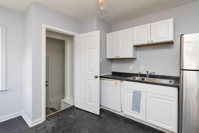 kitchen featuring white dishwasher, stainless steel refrigerator, white cabinetry, and sink