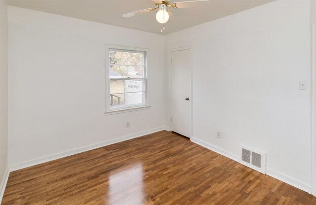 empty room with wood finished floors, baseboards, ceiling fan, and visible vents