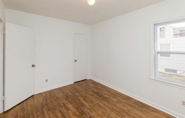 empty room with baseboards, wood finished floors, and a healthy amount of sunlight