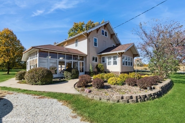 back of property featuring a sunroom and a lawn