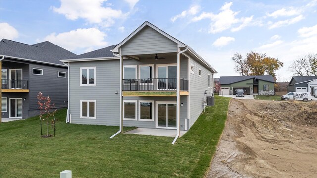 rear view of property featuring ceiling fan, a balcony, a yard, and a patio