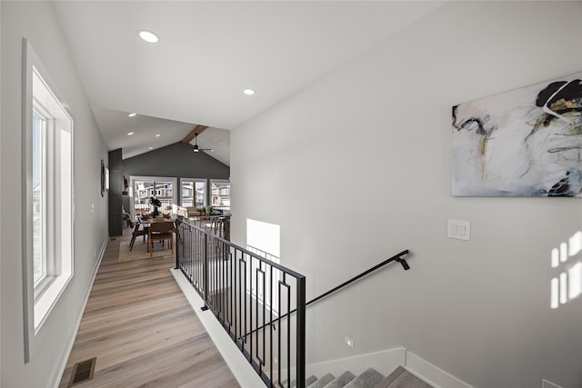 stairway with ceiling fan, lofted ceiling with beams, and hardwood / wood-style flooring