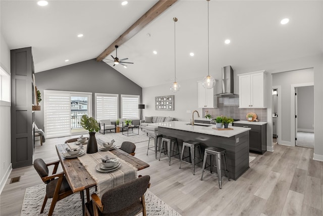 dining room featuring ceiling fan, lofted ceiling with beams, light wood-type flooring, and sink