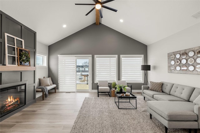 living room with a large fireplace, light hardwood / wood-style flooring, plenty of natural light, and ceiling fan