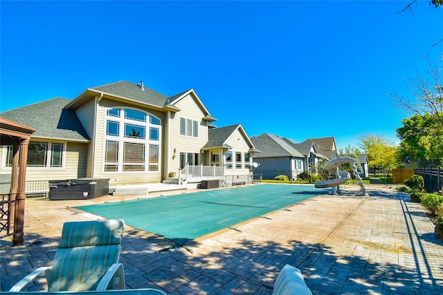 view of swimming pool with a patio area, a water slide, and a deck