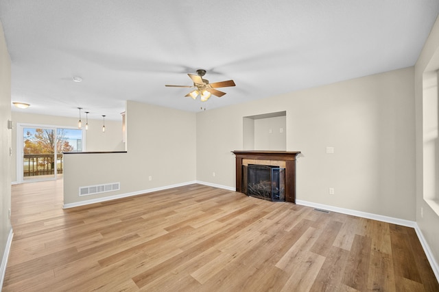 unfurnished living room featuring light hardwood / wood-style flooring, ceiling fan, and a tile fireplace