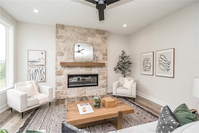 living room featuring a healthy amount of sunlight, a stone fireplace, and wood-type flooring