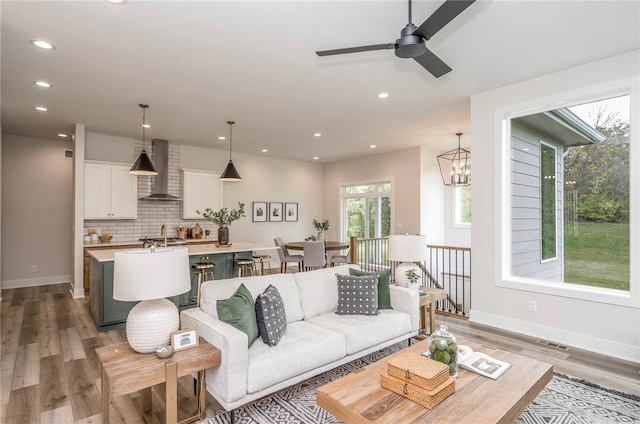 living room with sink, wood-type flooring, and ceiling fan with notable chandelier