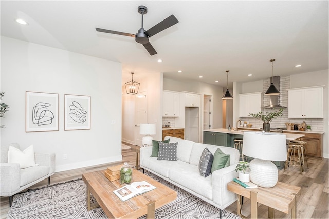 living room with sink, light hardwood / wood-style floors, and ceiling fan with notable chandelier