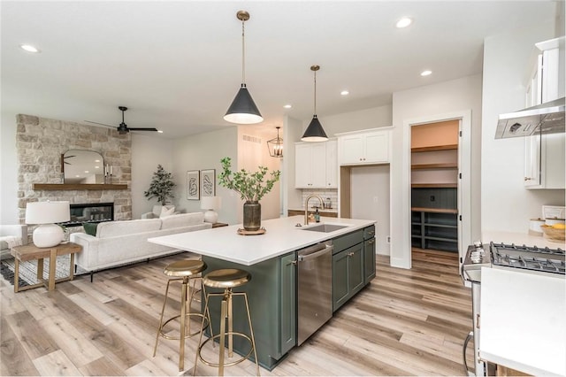 kitchen with pendant lighting, white cabinets, sink, stainless steel dishwasher, and an island with sink