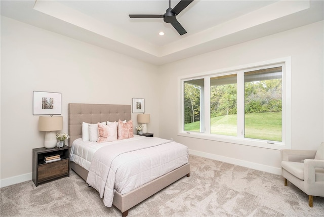 carpeted bedroom featuring ceiling fan and a raised ceiling