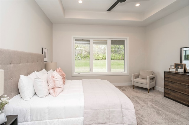 bedroom with light carpet, a raised ceiling, and ceiling fan