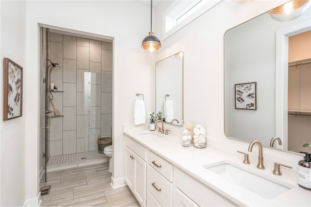 bathroom with a tile shower, vanity, and toilet