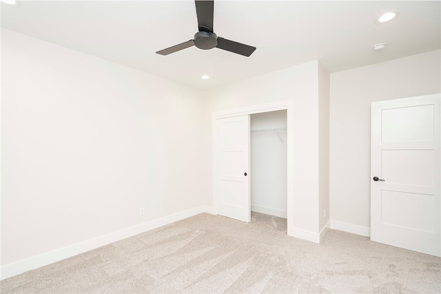 unfurnished bedroom featuring ceiling fan, light colored carpet, and a closet