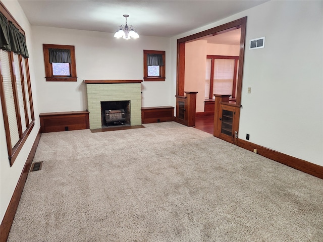 unfurnished living room featuring carpet flooring, a fireplace, and a chandelier