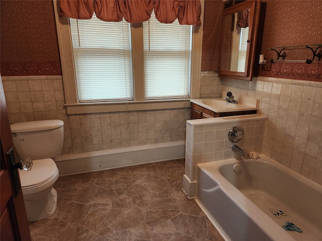 bathroom featuring a tub to relax in, vanity, toilet, and tile walls