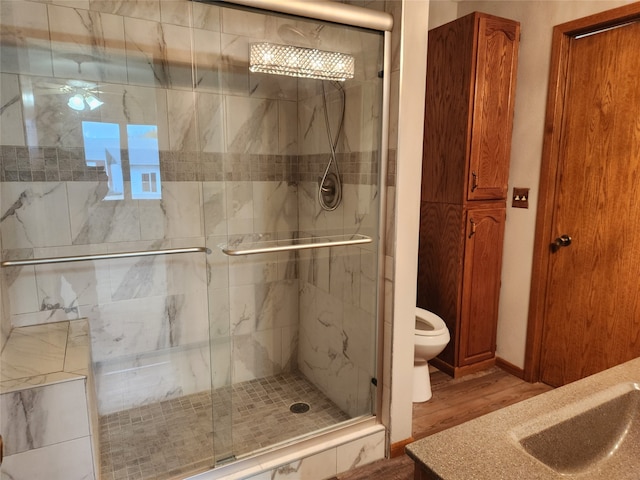 bathroom featuring toilet, hardwood / wood-style flooring, sink, ceiling fan, and walk in shower