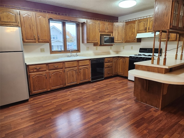 kitchen featuring a kitchen bar, a textured ceiling, sink, dark hardwood / wood-style floors, and white appliances