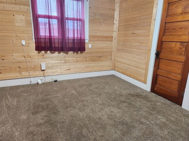 spare room featuring carpet and wood walls