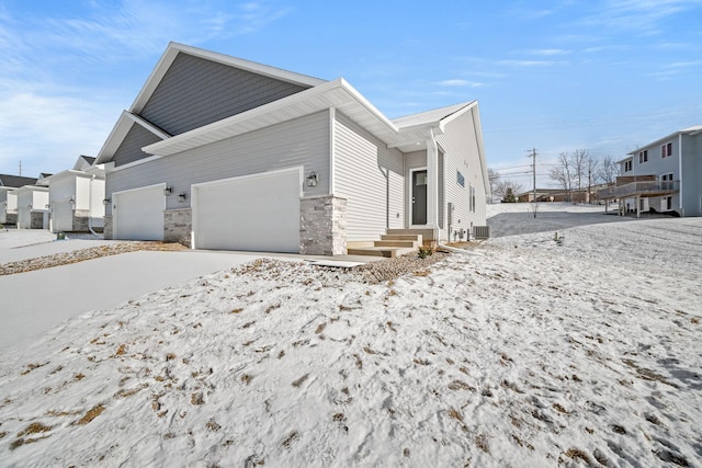 view of snow covered exterior featuring a garage and central AC unit