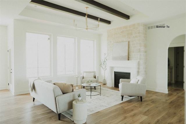 living room with a large fireplace, beam ceiling, and light wood-type flooring