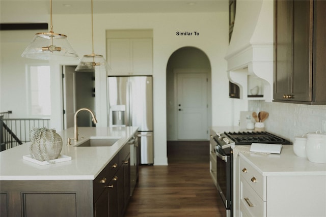 kitchen with pendant lighting, stainless steel range, dark brown cabinetry, and sink