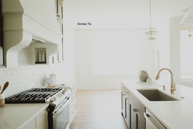 kitchen with tasteful backsplash, stainless steel appliances, light wood-type flooring, pendant lighting, and sink