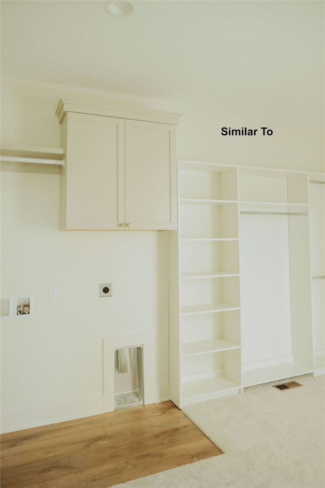 laundry room with hookup for an electric dryer, cabinets, and hardwood / wood-style flooring