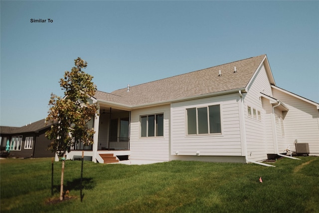 rear view of house featuring central air condition unit and a yard