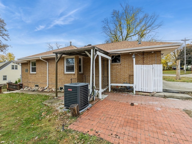 rear view of house featuring a lawn, cooling unit, and a patio area