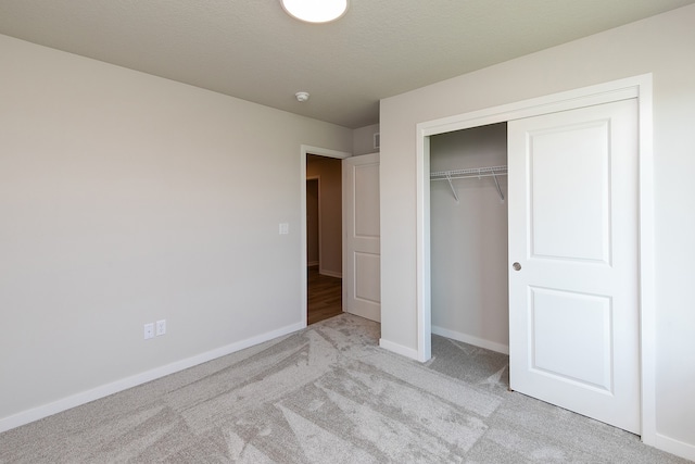 unfurnished bedroom featuring a closet, a textured ceiling, and light colored carpet