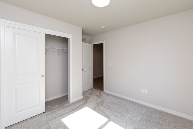 unfurnished bedroom with light carpet and a closet