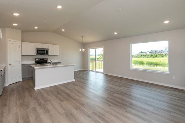 kitchen with stainless steel appliances, lofted ceiling, light wood-type flooring, and decorative light fixtures