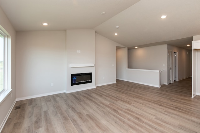 unfurnished living room featuring light hardwood / wood-style flooring, lofted ceiling, and heating unit