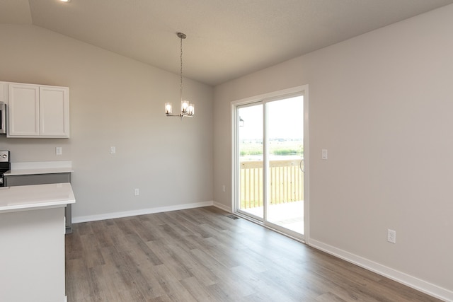 unfurnished dining area with lofted ceiling, an inviting chandelier, and light hardwood / wood-style flooring