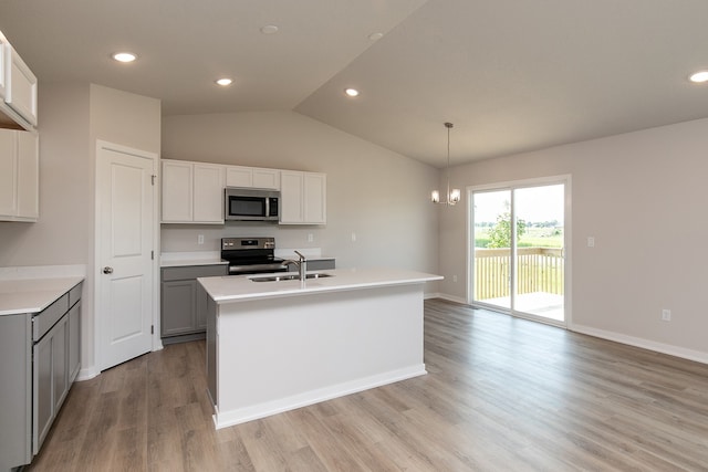 kitchen with lofted ceiling, a center island with sink, pendant lighting, and appliances with stainless steel finishes