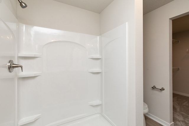 bathroom with toilet, a textured ceiling, and walk in shower