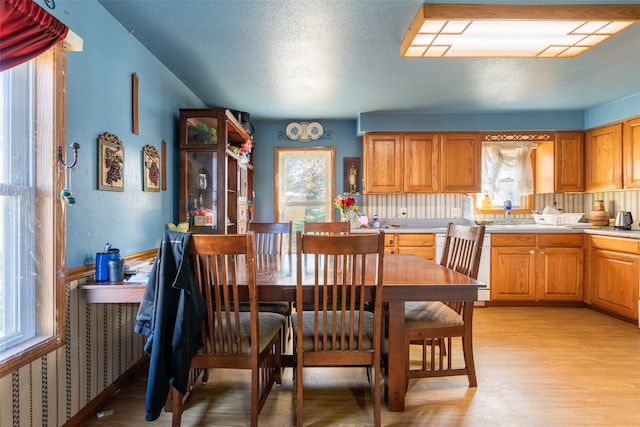 dining space featuring light wood-type flooring and a textured ceiling