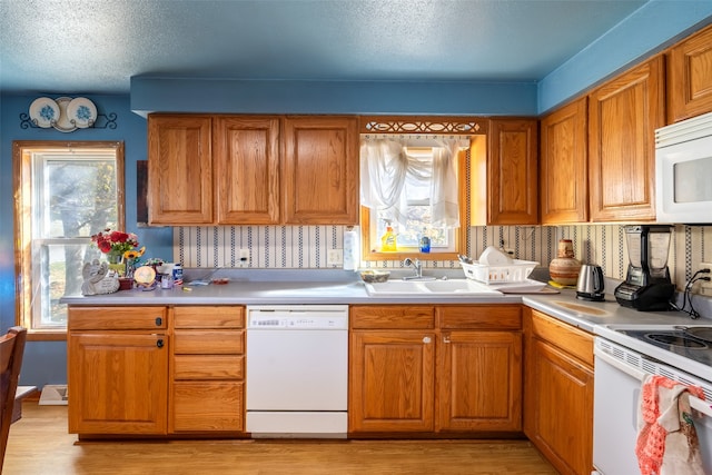 kitchen featuring white appliances, a textured ceiling, sink, and light hardwood / wood-style floors