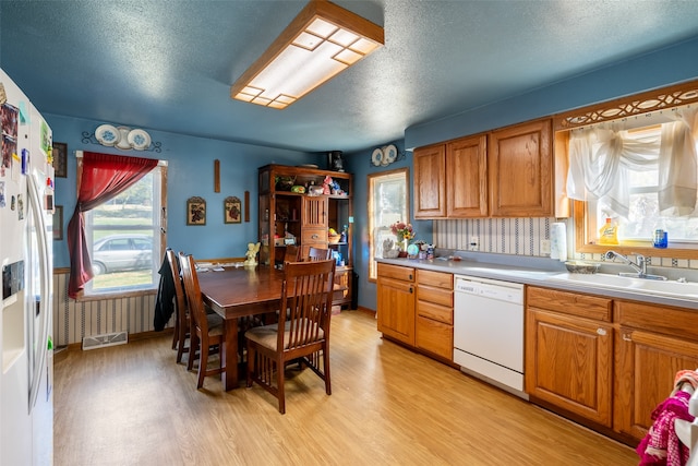 kitchen with a textured ceiling, sink, light hardwood / wood-style flooring, and dishwasher