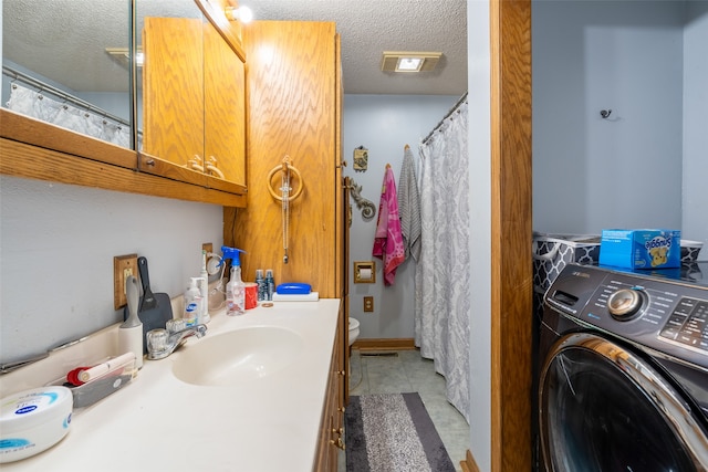 bathroom with toilet, tile patterned floors, a textured ceiling, vanity, and washer / clothes dryer