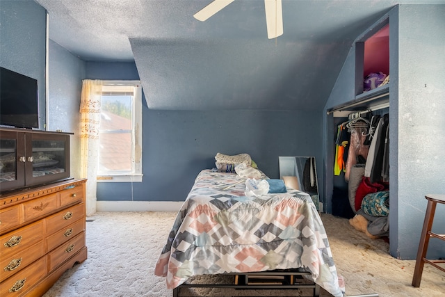 carpeted bedroom featuring a closet, vaulted ceiling, ceiling fan, and a textured ceiling