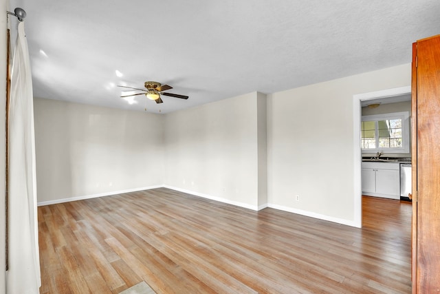 unfurnished room with light wood-type flooring, sink, and ceiling fan