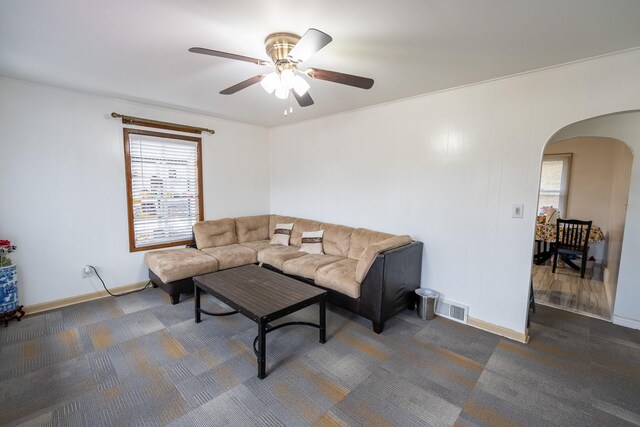 living room featuring ceiling fan and dark carpet